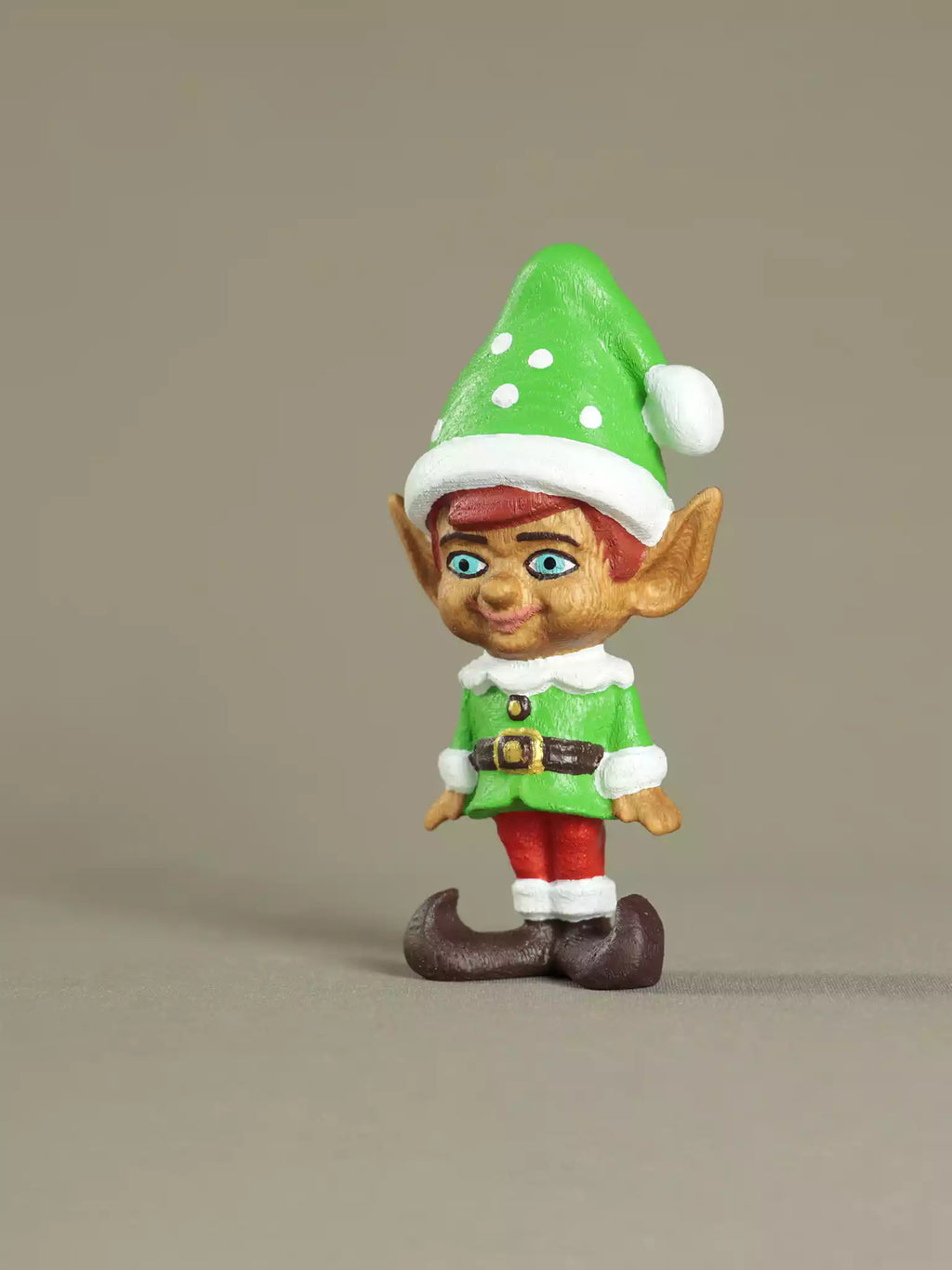 Elf figurine with green hat and red pants on a beige background