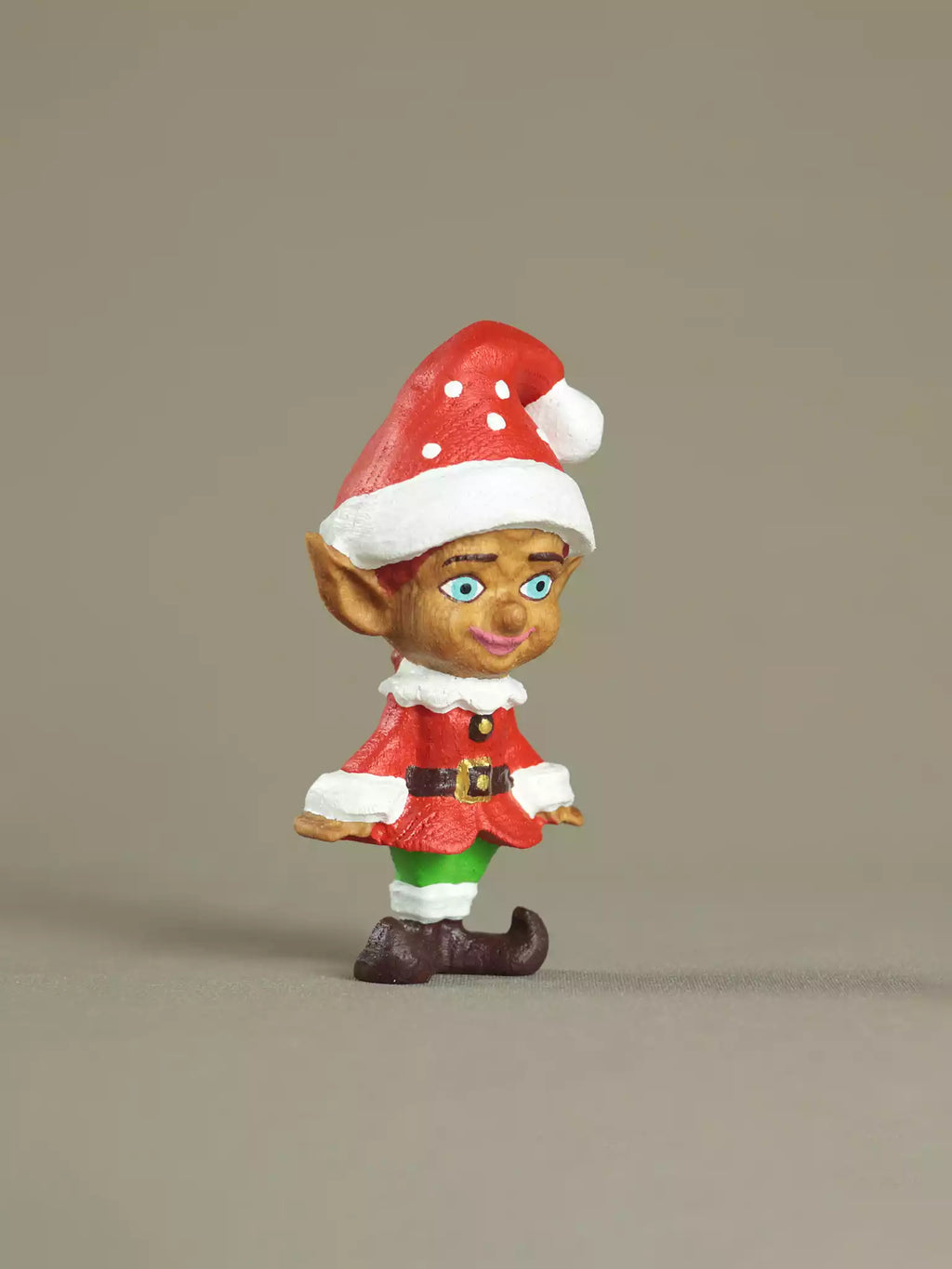 Christmas elf figurine with a red hat and outfit on a beige background