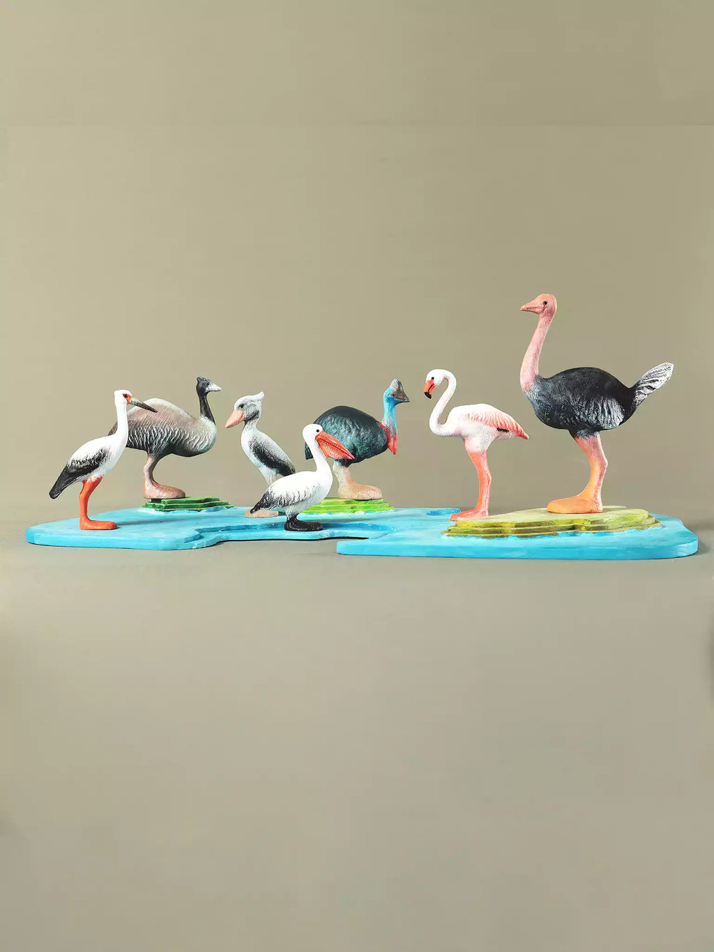 Wooden bird toy set arranged on blue puzzle base with handcrafted species like pelican and ostrich.