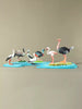 Eco-friendly hand-painted bird figurines displayed on wooden water and island map board.