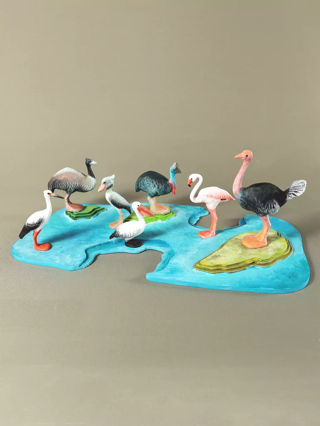 Set of seven wooden collectible birds displayed on a colorful map-like base, showcasing their detailed craftsmanship and vibrant colors.