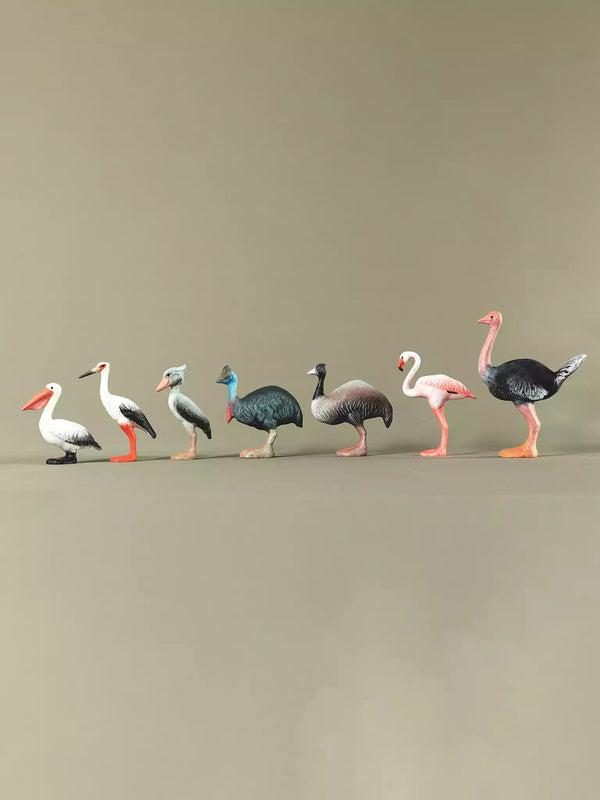 Collection of seven large wooden bird figurines displayed side by side on a neutral backdrop, highlighting their size and variety.