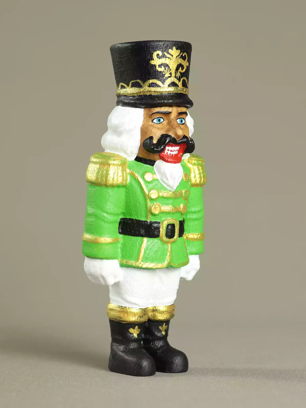 Nutcracker figurine in green uniform with black top hat on a beige background