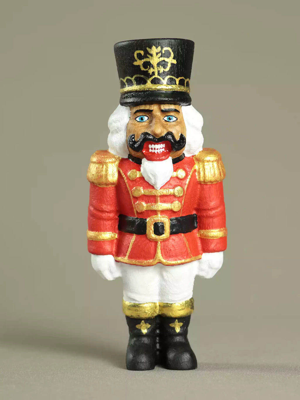 Nutcracker figurine with red uniform and black hat on a beige background