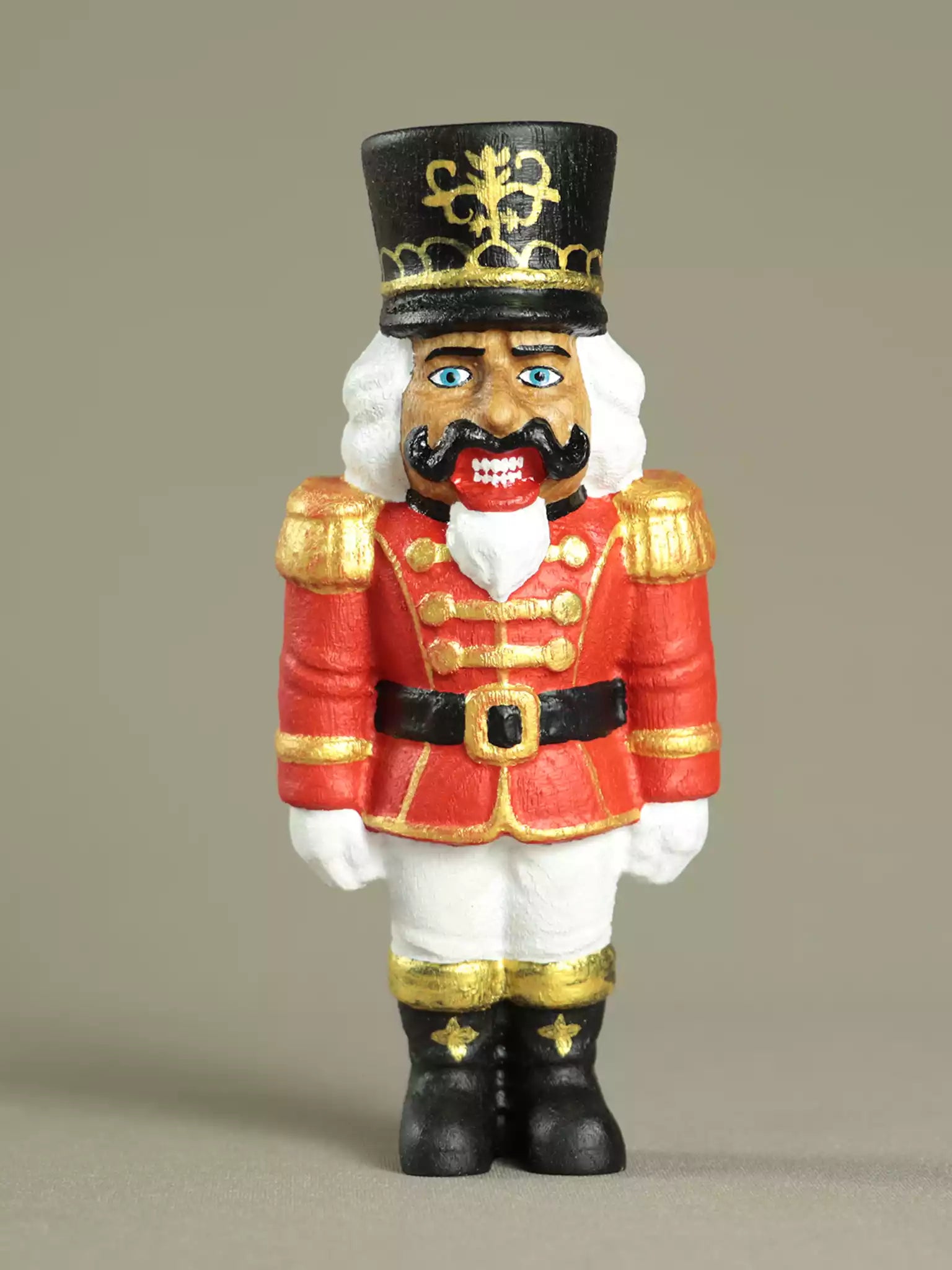 Nutcracker figurine with red uniform and black hat on a beige background