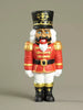 Nutcracker figurine with red uniform and black hat on a beige background