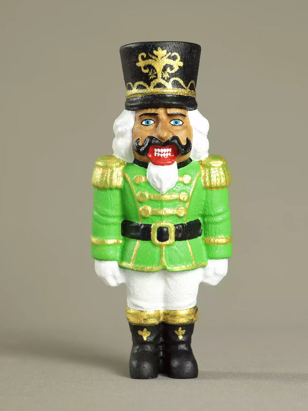 Toy figure of a nutcracker in green uniform with a black hat on a beige background