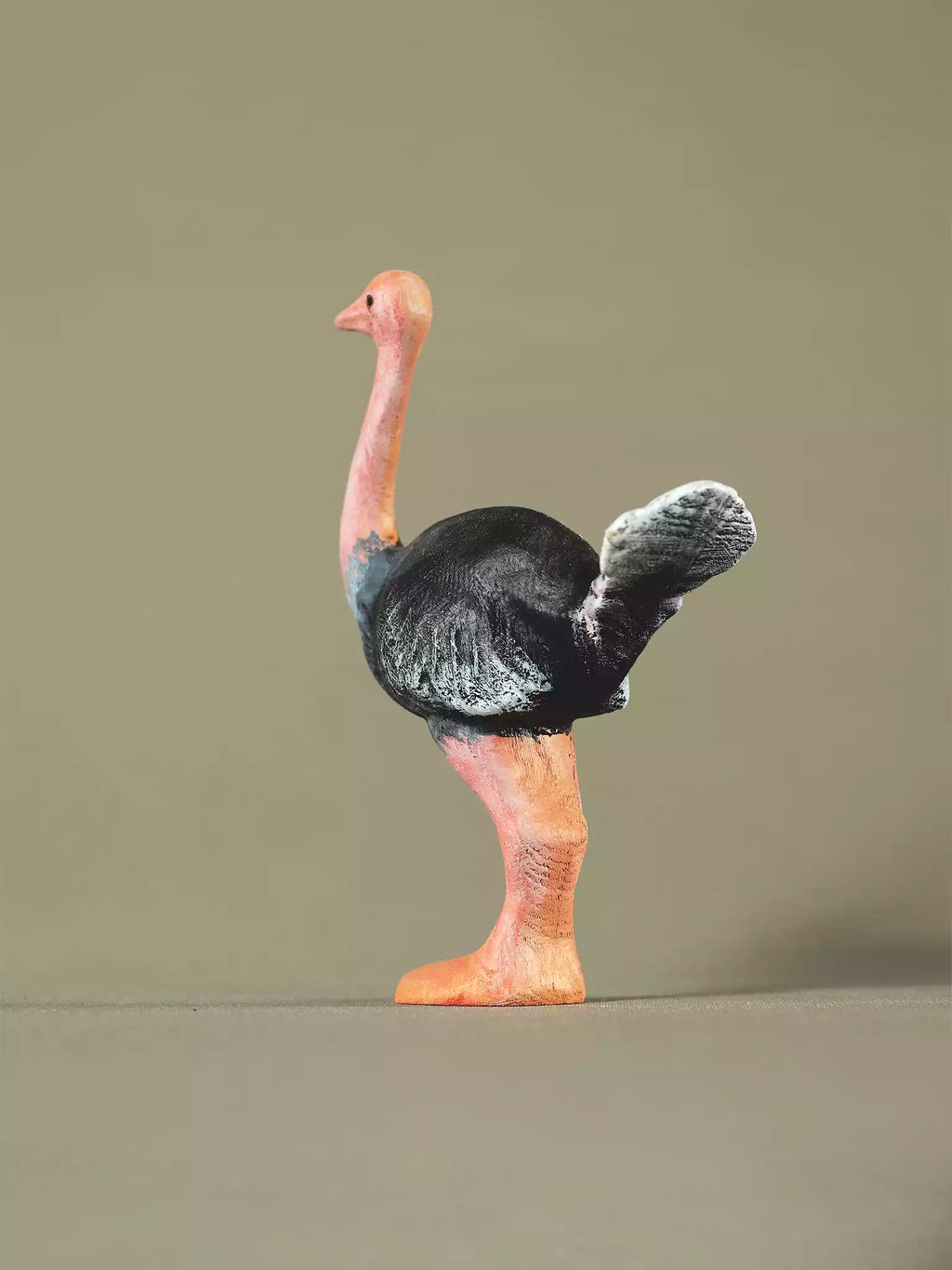 Rear angle of a hand-painted wooden ostrich toy showing detailed feathers and stance.