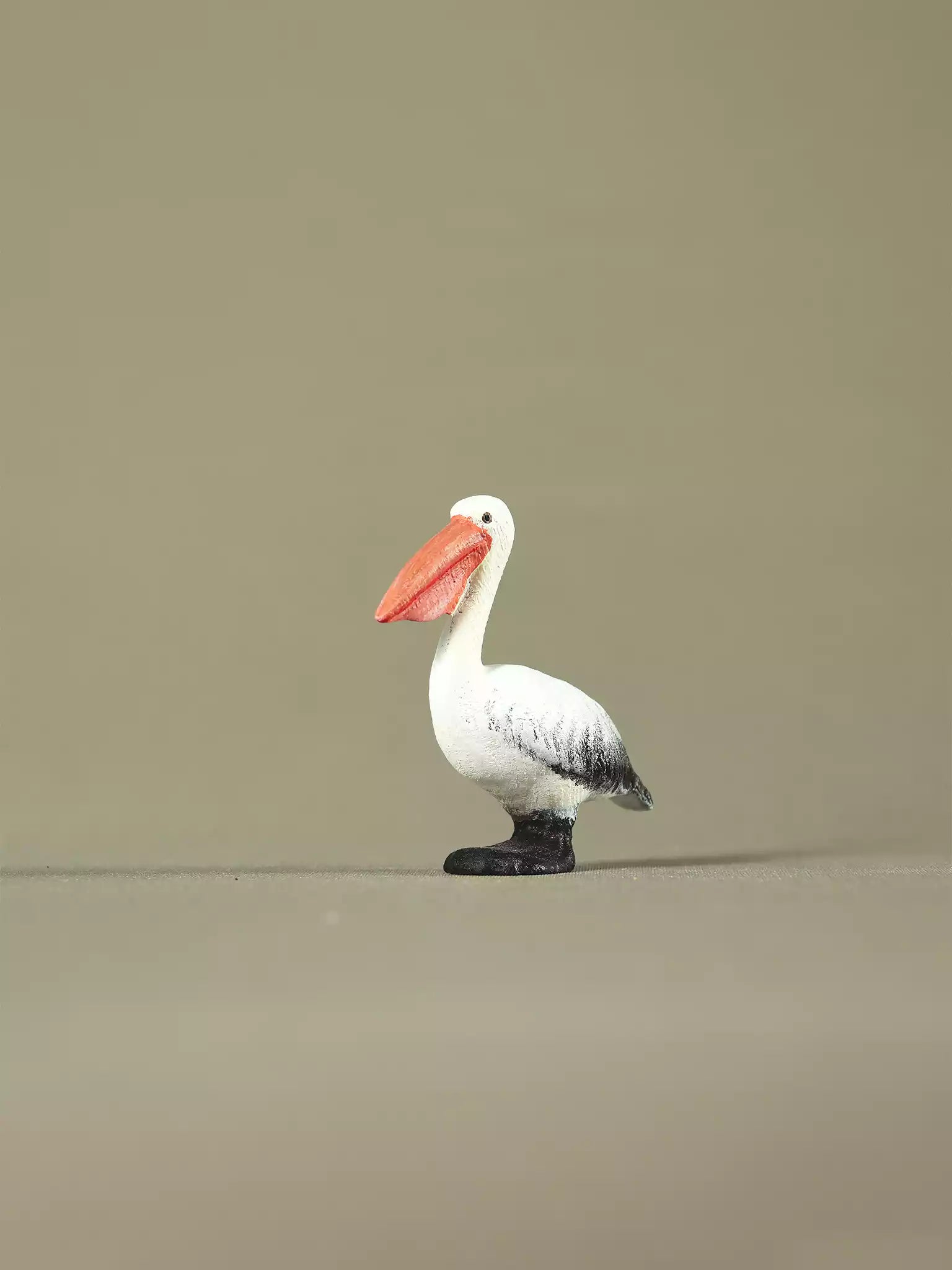 Hand-painted wooden pelican toy standing upright, shown in a neutral background with its orange beak and black-and-white body