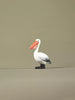 Hand-painted wooden pelican toy standing upright, shown in a neutral background with its orange beak and black-and-white body