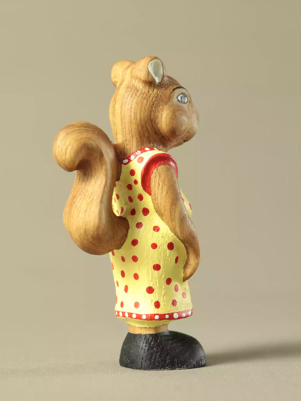 Wooden squirrel figurine in yellow dress with red dots
