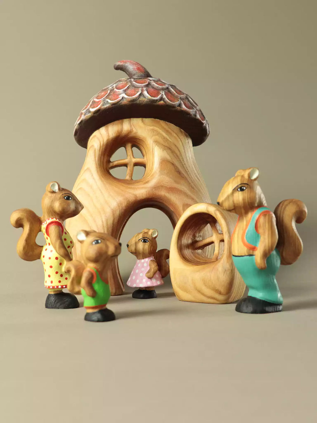Wooden fairy acorn house with squirrel figurines on a beige background