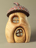 Wooden fairy house with an acorn roof on a beige background