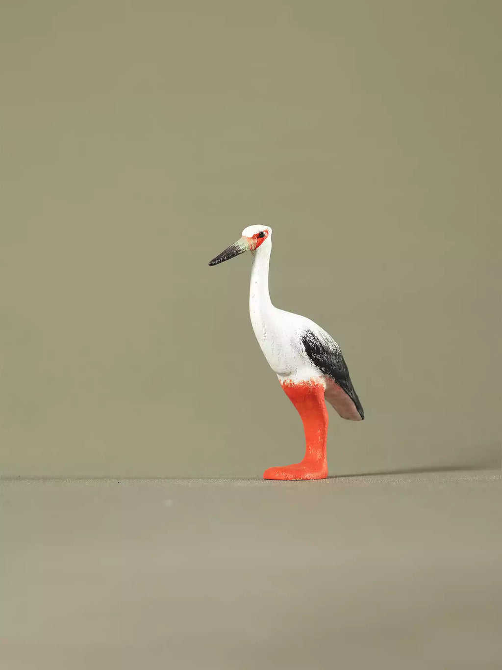 Hand-painted wooden stork toy standing upright on a neutral background, featuring orange legs and black-and-white feathers.