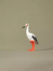 Hand-painted wooden stork toy standing upright on a neutral background, featuring orange legs and black-and-white feathers.