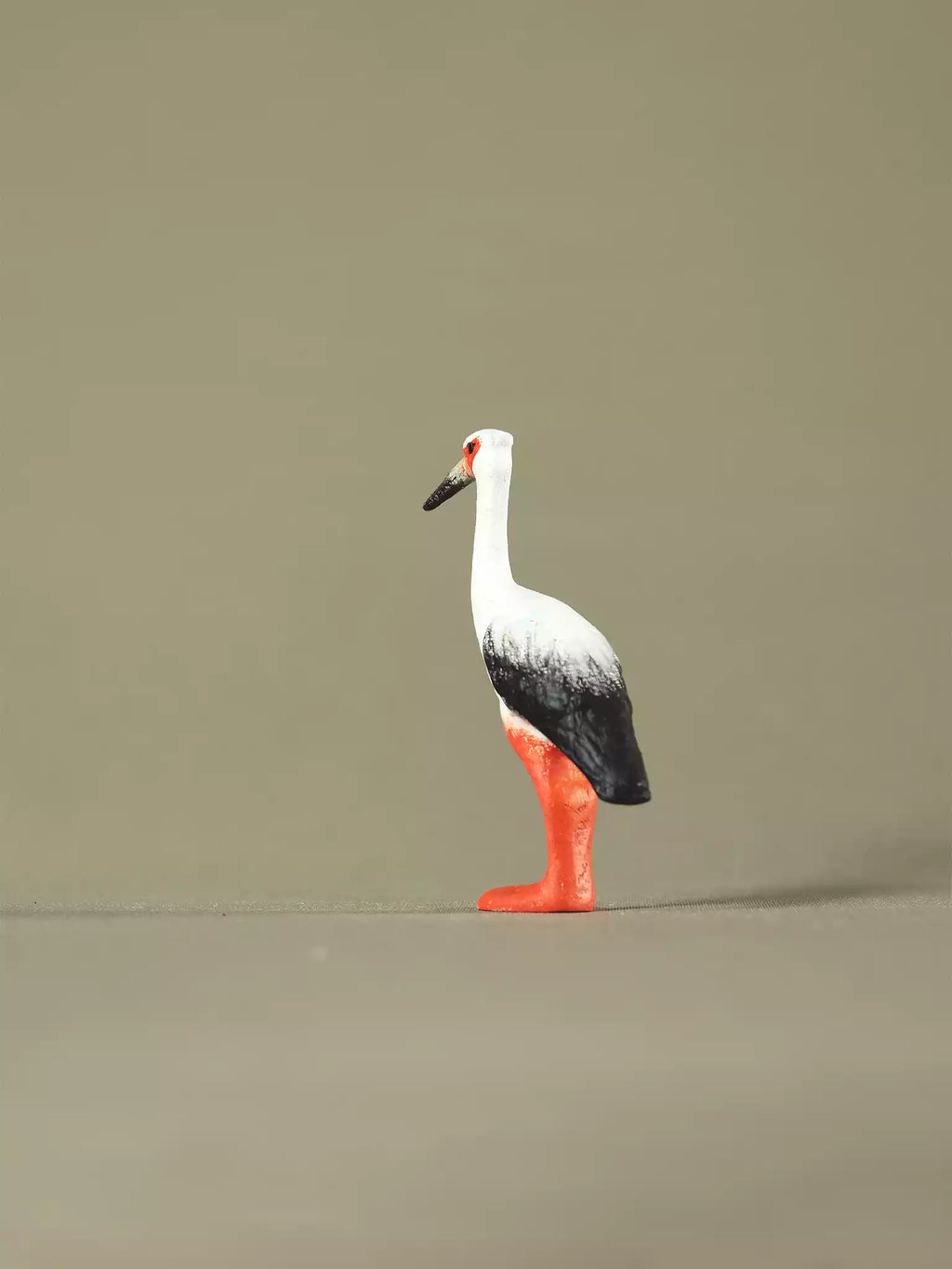 Minimalist product image of a handcrafted stork toy displayed on a plain surface with soft lighting.
